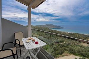 a table on a balcony with a view of the ocean at The Village Apartments in Plakias