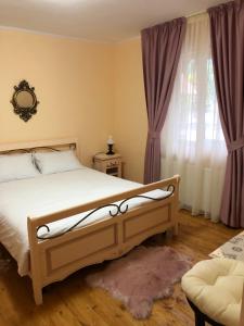 a bedroom with a bed and a window with curtains at Pensiunea Valea Gepisului in Groşi +39 photos