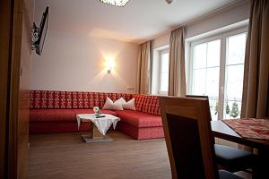 a living room with a red couch and a table at Villa Sepp in Ramsau im Zillertal