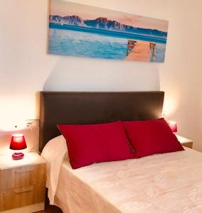 - une chambre dotée d'un lit avec des oreillers rouges et un tableau dans l'établissement Apartamento El Barco 1 linea PLAYA, PARKING, WIFI, à Torrox Costa