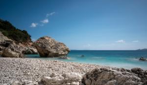 a rocky beach with people swimming in the ocean at Sivros Stone Cottages in Sívros