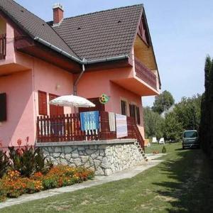 a pink house with a balcony with an umbrella at Tóth nyaraló in Balatongyörök