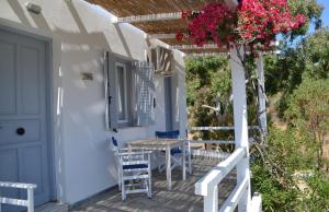 a porch with a table and chairs and flowers at Paleochori Studios in Paliochori