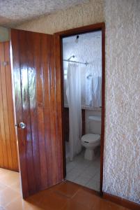 a bathroom with a toilet and a glass door at Hotel Tankah Cancun in Cancún