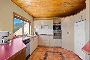 a kitchen with white cabinets and a wooden ceiling at Amazing View Home in Queenstown
