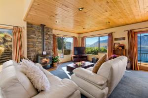 a living room with two white couches and a fireplace at Amazing View Home in Queenstown