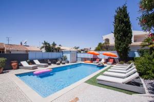 - une piscine avec des chaises longues et des parasols dans l'établissement Horta's villa - private heatable Pool, à Lagos