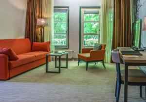 een woonkamer met een bank en een stoel bij Parkhotel Tjaarda in Oranjewoud