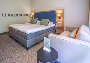 een hotelkamer met 2 bedden en een bank bij Parkhotel Tjaarda in Oranjewoud