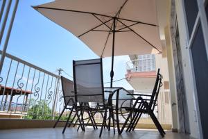 a table and chairs with an umbrella on a balcony at alexandras lux apartments flogita in Flogita
