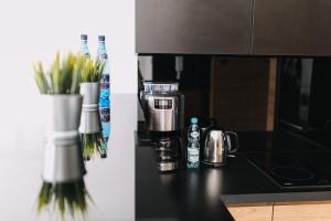 a kitchen counter with a coffee maker and a vase of flowers at Hypnotize Apartment in Konin