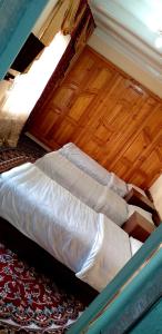 a bed in a room with a wooden floor at Guest House Firuza in Samarkand