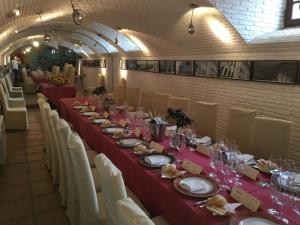 een lange tafel met rode tafelkleden en witte stoelen bij Hotel El Carmen in Puente-Genil