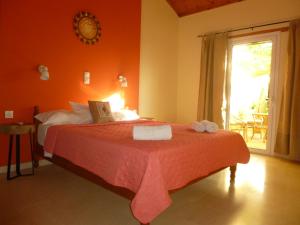 a bedroom with a bed with orange walls and a window at Athina Apartments in Arillas