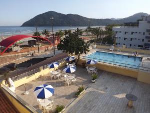 uma piscina com mesas e guarda-sóis junto à praia em 27 Praia Hotel - Frente Mar em Bertioga