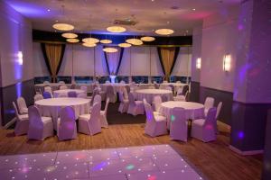 a room with tables and chairs and purple lighting at The Georgian hotel in Coatbridge