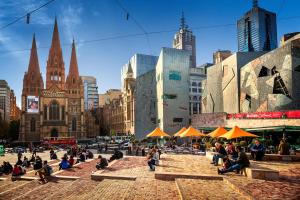 a group of people sitting on a sidewalk in a city at Flinders Landing Apartments in Melbourne