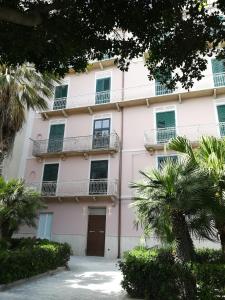 ein rosafarbenes Gebäude mit Balkonen und Bäumen in der Unterkunft Pappalardo - Regina Elena in Trapani
