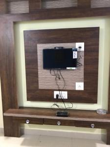 Highland Inn Hotel في منغالور: تلفزيون بشاشة مسطحة على جدار خشبي