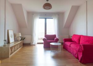 a living room with a red couch and a chair at Rewska Przystań - Dom z balią ogrodową i sauną in Rewa