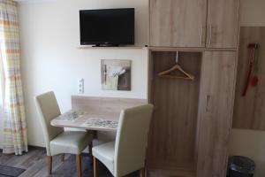 a dining room table with two chairs and a tv at Pension Jahnkes Gasthaus in Todesfelde
