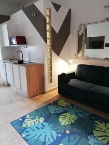 a living room with a black couch and a kitchen at Pappalardo - Regina Elena in Trapani