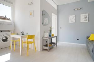 a white living room with a table and yellow chairs at University of Bologna & Porta San Donato Apartment in Bologna