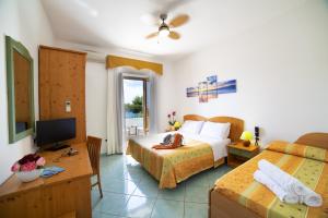 una camera d'albergo con due letti e una televisione di Hotel La Mandorla a Ischia