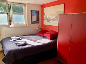 a bedroom with red walls and a bed with towels on it at Houseboat Westerdok in Amsterdam