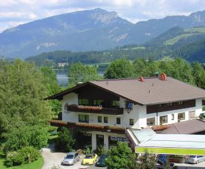 budynek z samochodami zaparkowanymi przed nim z górami w obiekcie Ferienwohnungen Greiderer Walchsee w mieście Walchsee