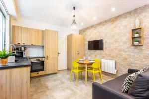 a kitchen and living room with a table and yellow chairs at CMG Oberkampf/ Charonne C in Paris