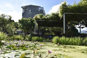un jardín con lirios y un edificio de fondo en Rainbow Bridge B&B en Sanzhi