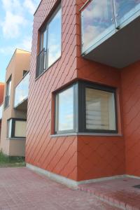 a red building with windows on the side of it at Family friendly Apartment Baltic Seaside in Šventoji