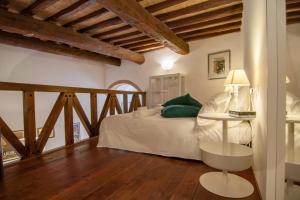 Umbrian Concierge - Cozy Loft Vannucci في بيروجيا: غرفة نوم بسرير ومخدات خضراء وطاولة