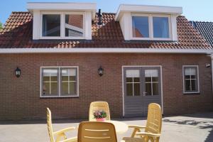 eine Terrasse mit Stühlen und einem Tisch vor einem Backsteinhaus in der Unterkunft Ons Kotje in Aagtekerke
