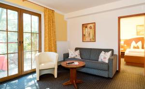ein Wohnzimmer mit einem Sofa, einem Tisch und einem Bett in der Unterkunft Hotel am Katharinenholz in Potsdam