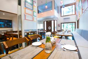 a dining room with tables and chairs and windows at VITS Sharanam, Thane in Thane