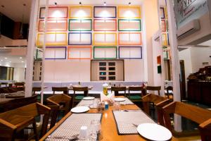 a dining room with tables and chairs and a wall with windows at VITS Sharanam, Thane in Thane
