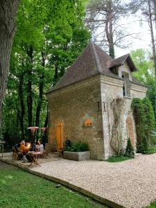 um pequeno edifício de tijolos com pessoas sentadas à mesa em Domaine du Chesney em Pressagny l'Orgueilleux
