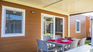 einen Tisch und Stühle auf einer Terrasse mit einem Tisch und einem Fenster in der Unterkunft IdeaLazise Camping and Village in Lazise