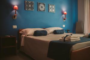 een slaapkamer met twee bedden met blauwe muren en lampen bij B&B DaBi in Alghero
