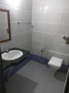 uma casa de banho com um lavatório, um WC e um espelho. em Hotel Surya em Mangalore