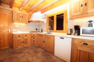 a kitchen with wooden cabinets and a white microwave at Chalet du Pre in Séez