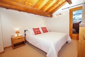a bedroom with a white bed and a wooden ceiling at Chalet du Pre in Séez