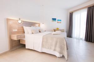 een slaapkamer met een groot bed met witte lakens bij Porfyris Studios and Apartments in Karpathos