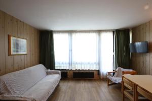 - un salon avec un canapé et une grande fenêtre dans l'établissement Appartamenti Roulette Montana Marilleva 900, à Mezzana