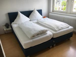 - 2 lits avec des draps blancs et des oreillers dans l'établissement Landhaus Wiesemann Parkappartements & Dependance - Nähe Ettelsberg-Talstation, à Willingen