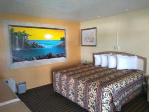 a hotel room with a bed and a painting on the wall at Super Inn Daytona Beach in Daytona Beach