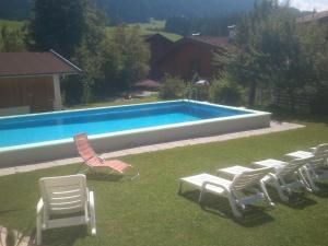 a group of lawn chairs and a swimming pool at Pension Alpenstern in Oberau