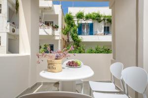 - une table et des chaises blanches sur un balcon avec un bol de fruits dans l'établissement Villa Agape, à Naxos Chora